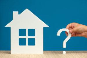 Die Wahl des Immobilienkaufs, der tatsächliche Wert des Hauses. Die Wahl zwischen großem und kleinem, teurem oder billigem Haus. Haus-Modell und Frage-Symbol in der Hand