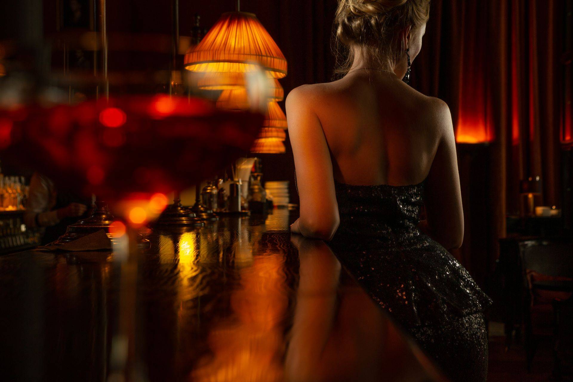 Frau in elegantem Abendkleid an einer stilvoll beleuchteten Bar in Hamburg