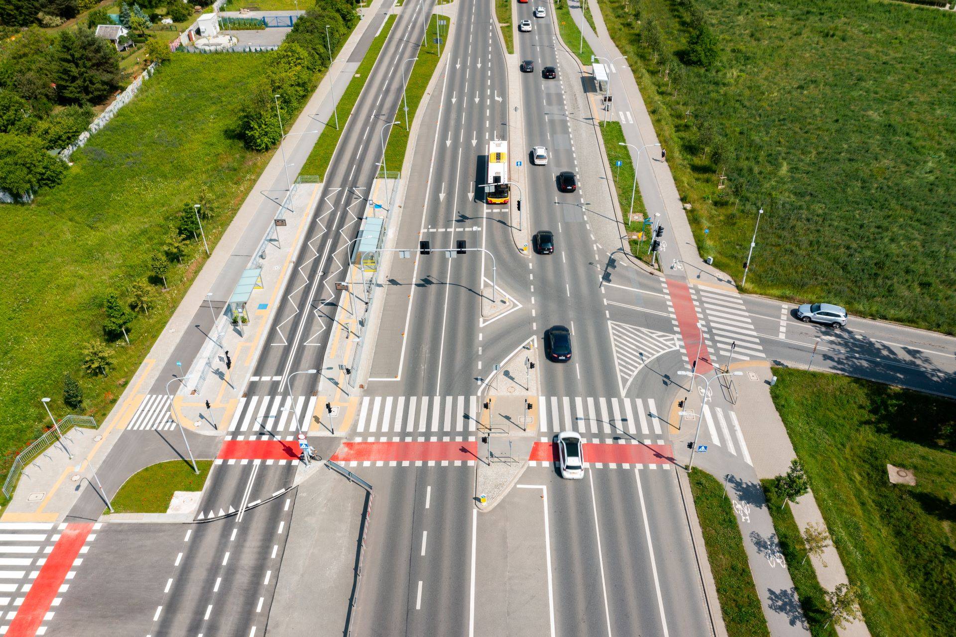 Große Kreuzung mit verschiedenen Fahrbahnmarkierungen und Verkehrsteilnehmern