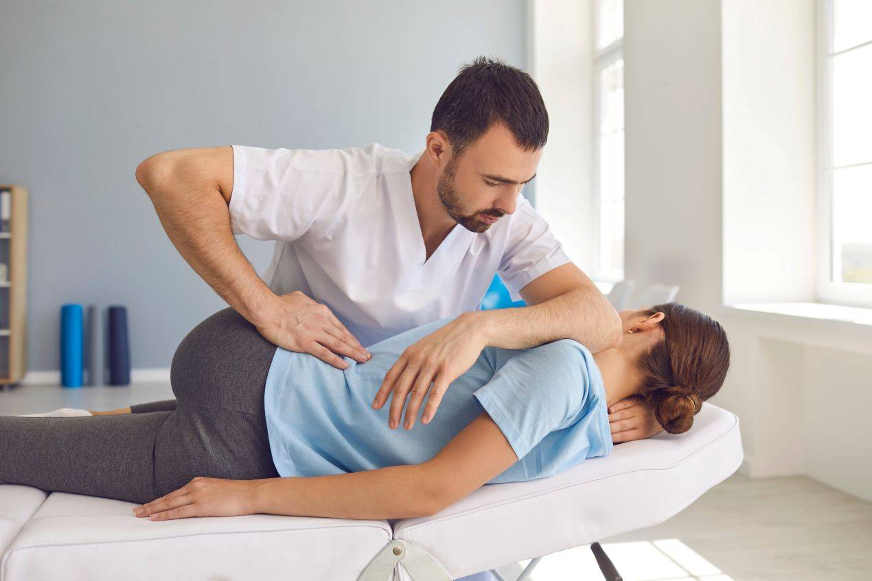 Ein Therapeut fuehrt eine gezielte Rueckenbehandlung bei einer Patientin durch – haeufig praktiziert in Osteopathie Freiburg Einrichtungen