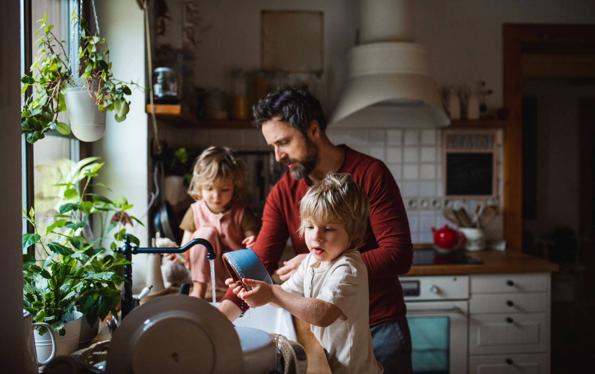 Vater mit zwei kleinen Kindern beim Abwasch in der Küche
