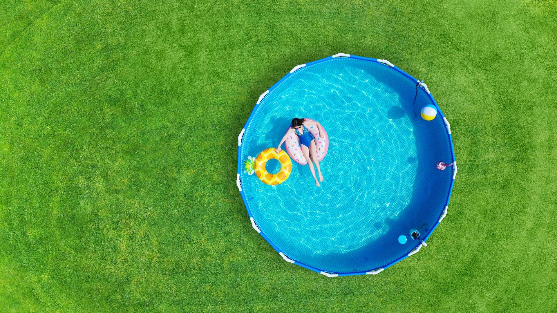 Frau entspannt auf Wasserreifen im blauen Gartenpool aus der Vogelperspektive | Pools