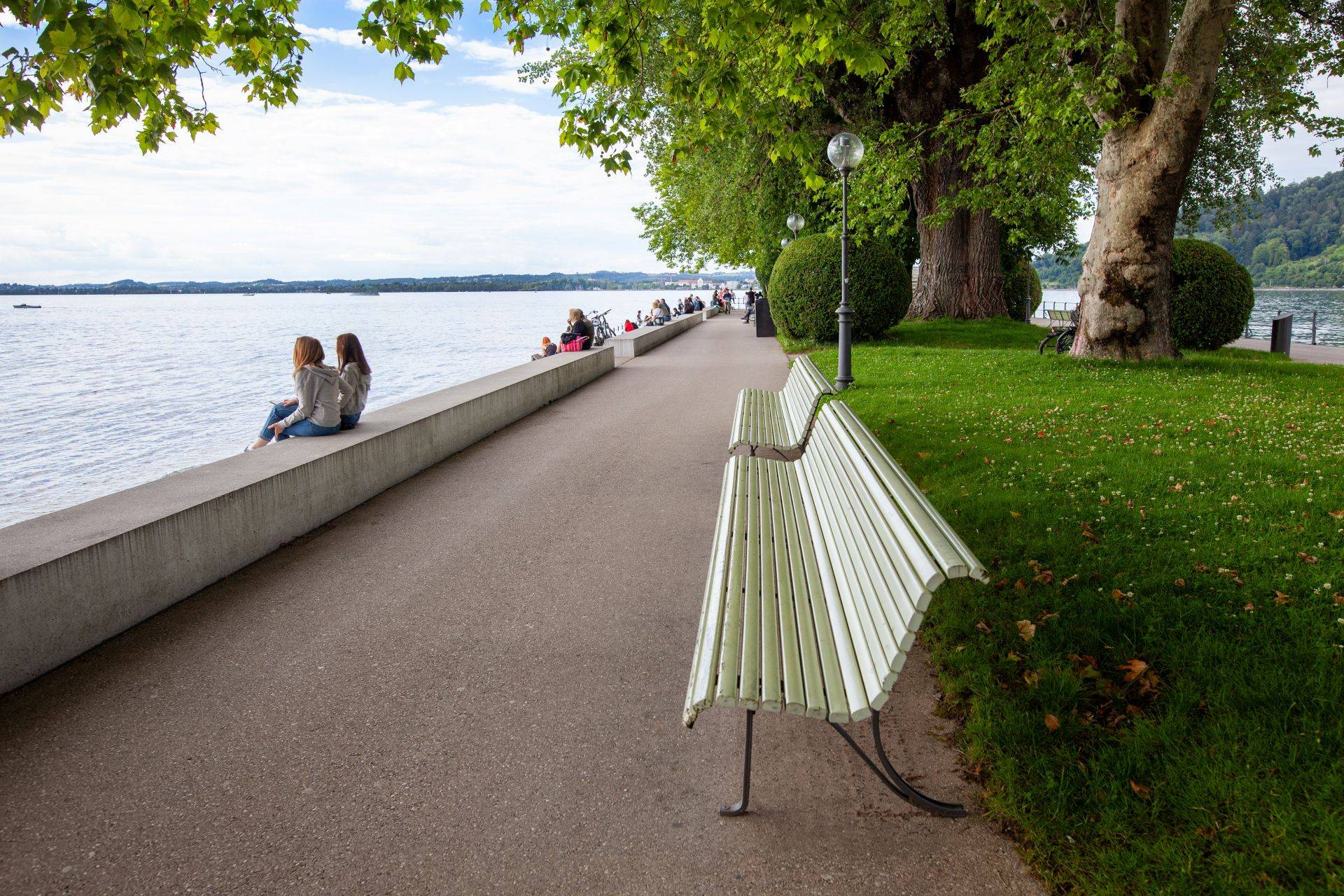 Uferpromenade am Bodensee mit Sitzbaenken und Ausblick, entspannter Moment beim Gruppenurlaub in einer Ferienwohnung Bodensee privat